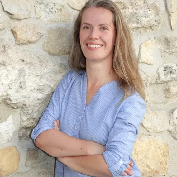 Bewerbungsbild einer jungen Frau vor einer hellen Mauer